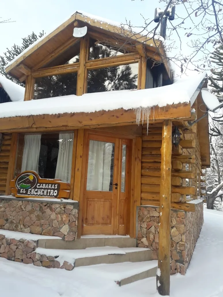 Entrada de la Cabaña 2 con nieve y el cartel de Cabañas El Encuentro