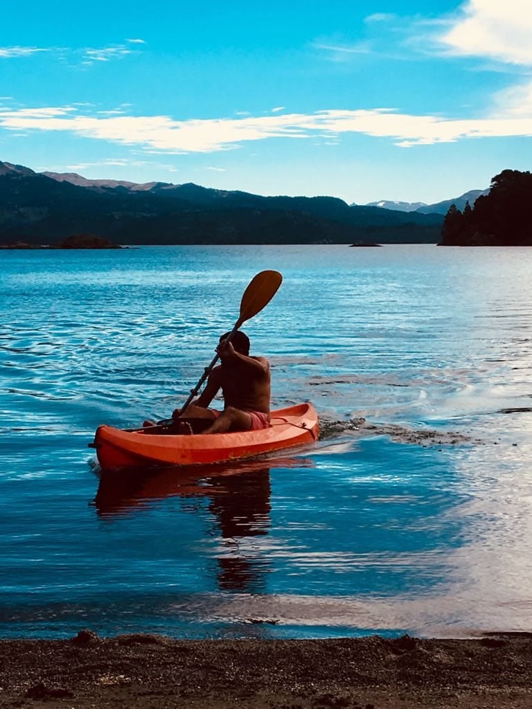 Persona remando en un kayak naranja sobre el lago