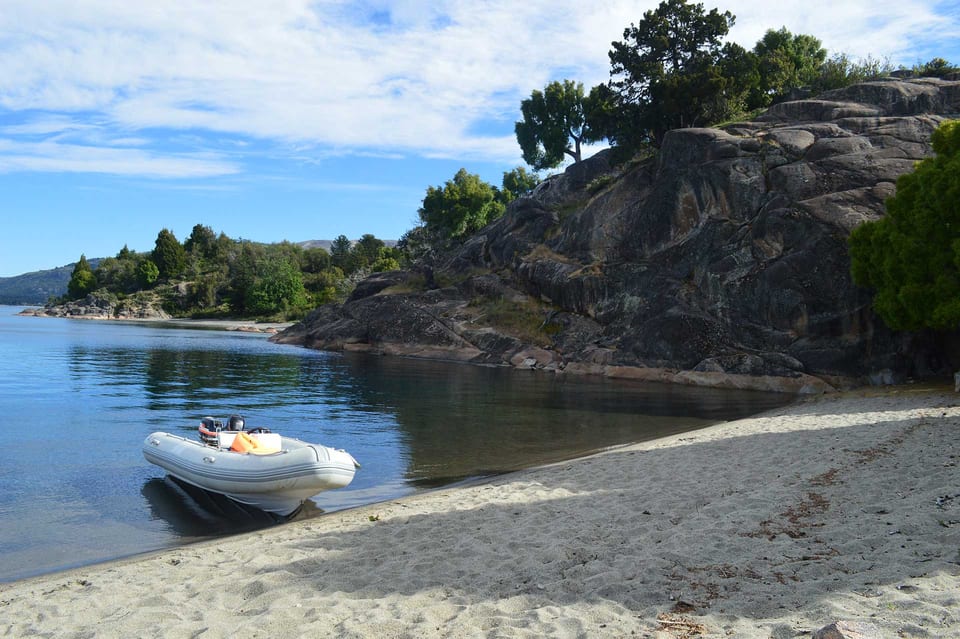 Bote inflable en una playa del lago junto a rocas y árboles