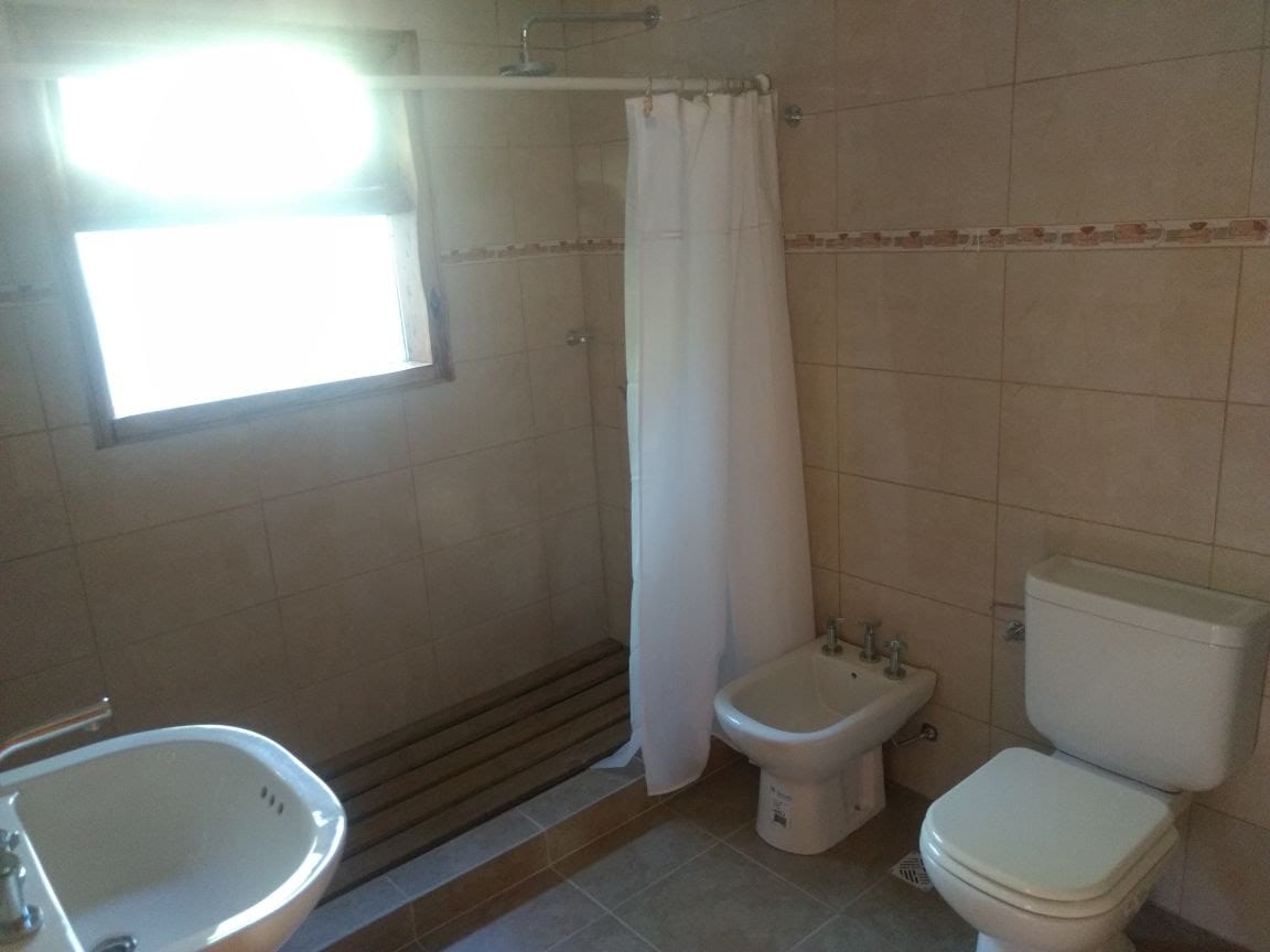 Baño con bidet, inodoro, lavamanos y ducha con cortina.