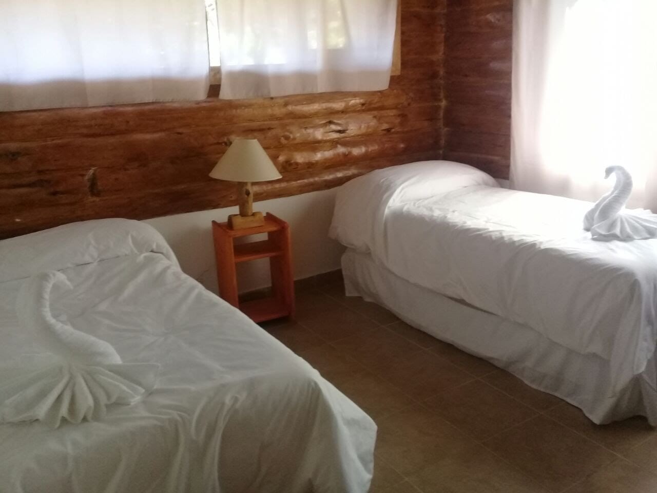Dormitorio con dos camas individuales y toallas decorativas sobre ellas.