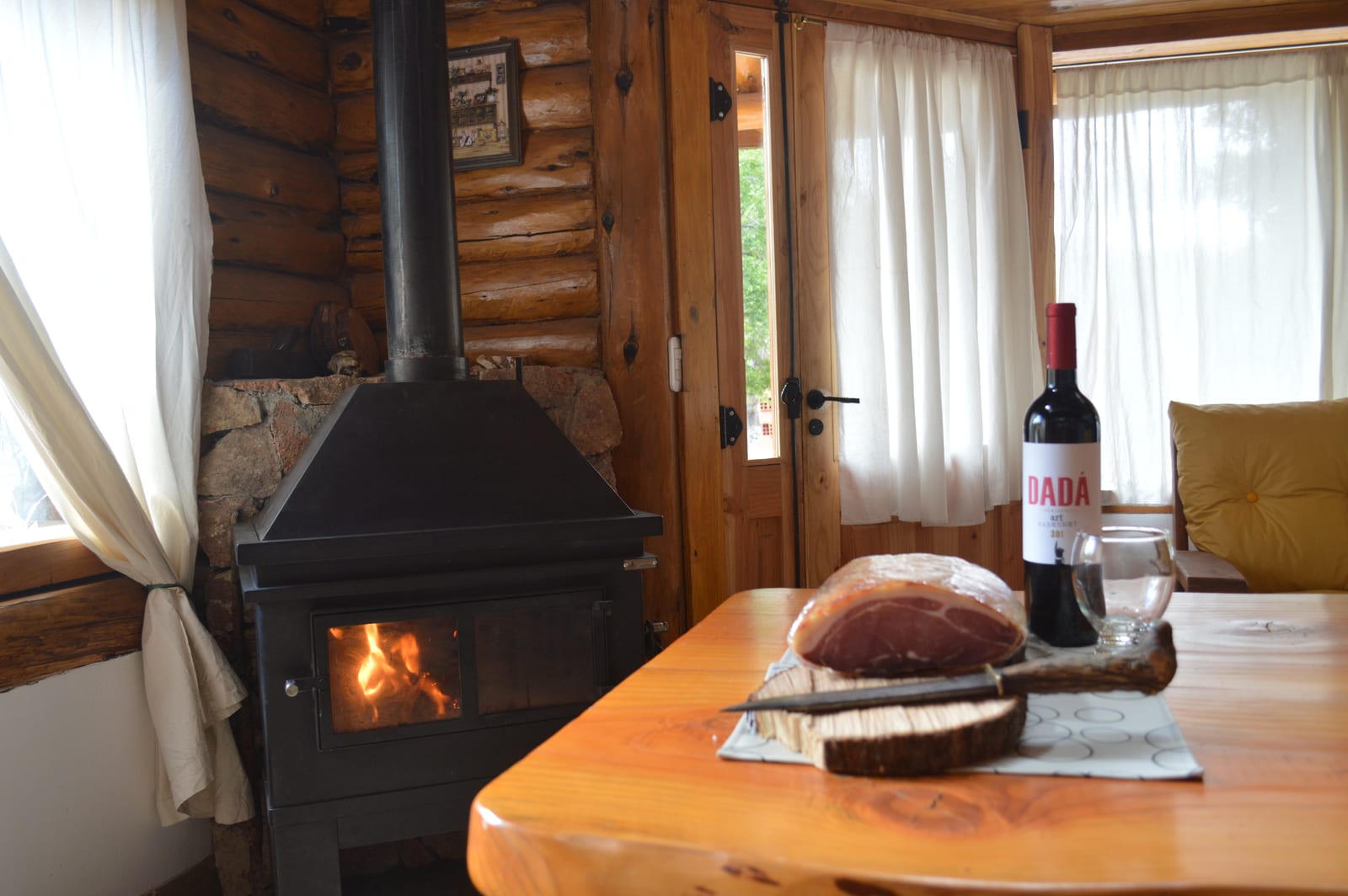 Hogar a leña encendido junto a una mesa con pan y vino.