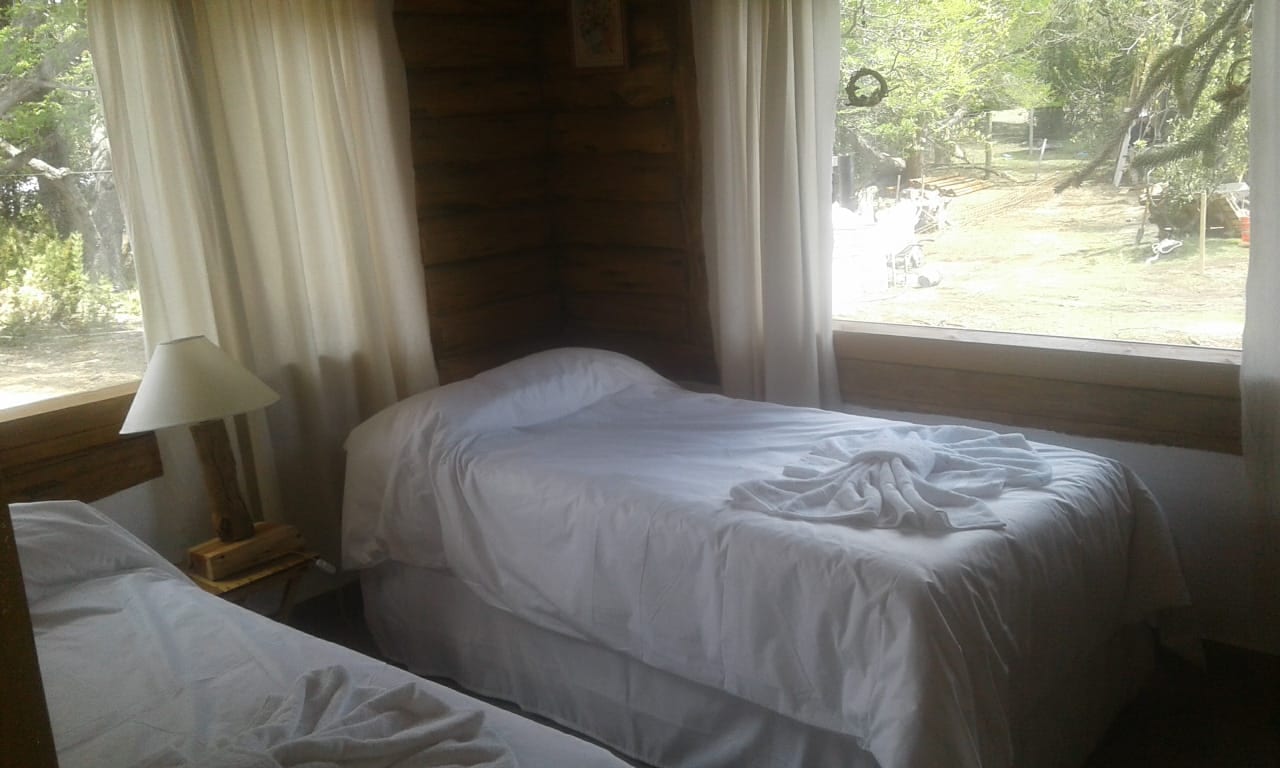 Dormitorio con camas blancas junto a las ventanas.