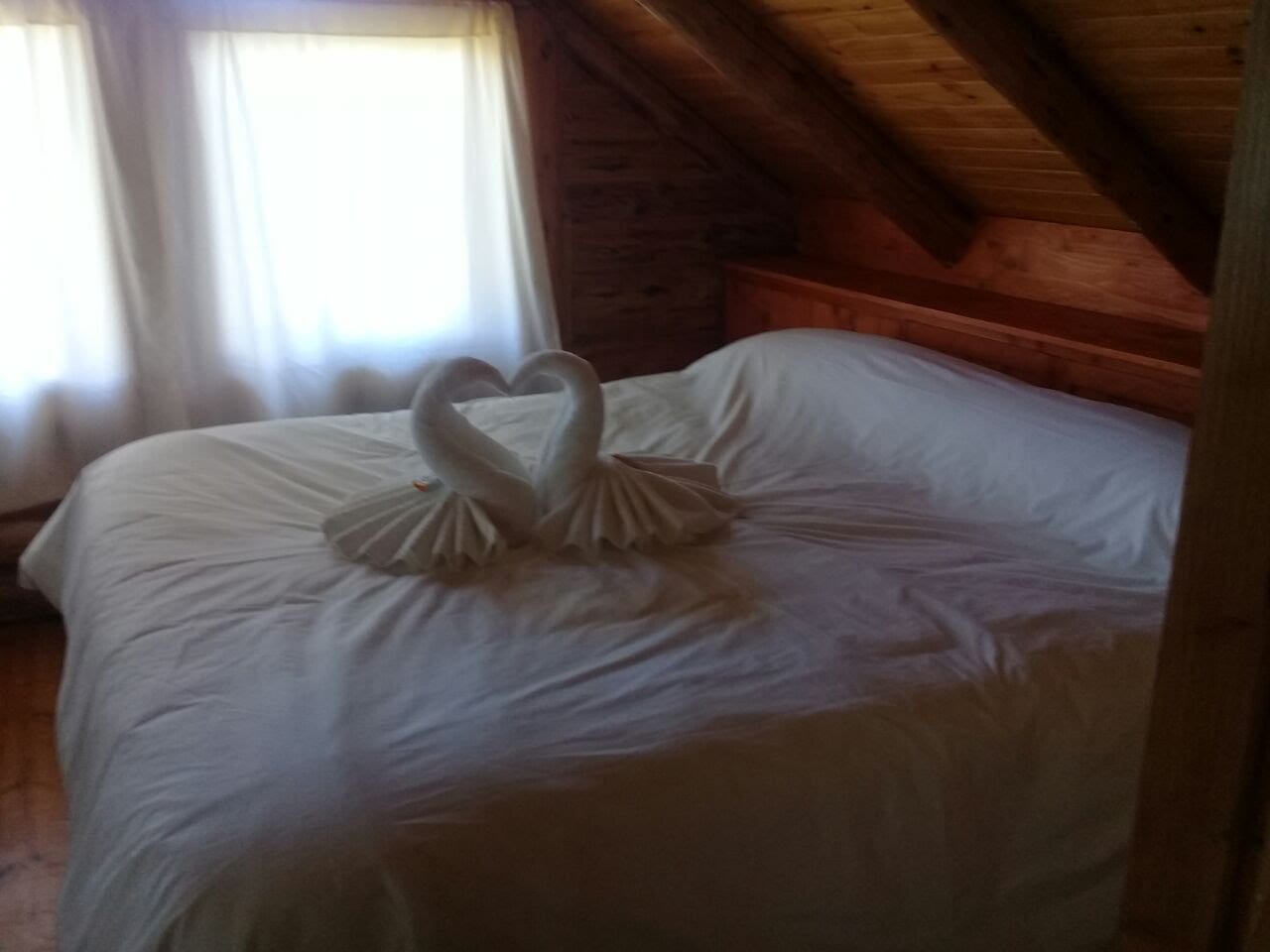 Cama doble con toallas decoradas en forma de cisne.