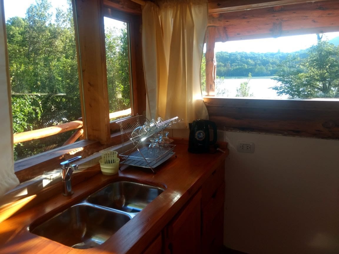 Cocina con bacha junto a una ventana con vista al lago.