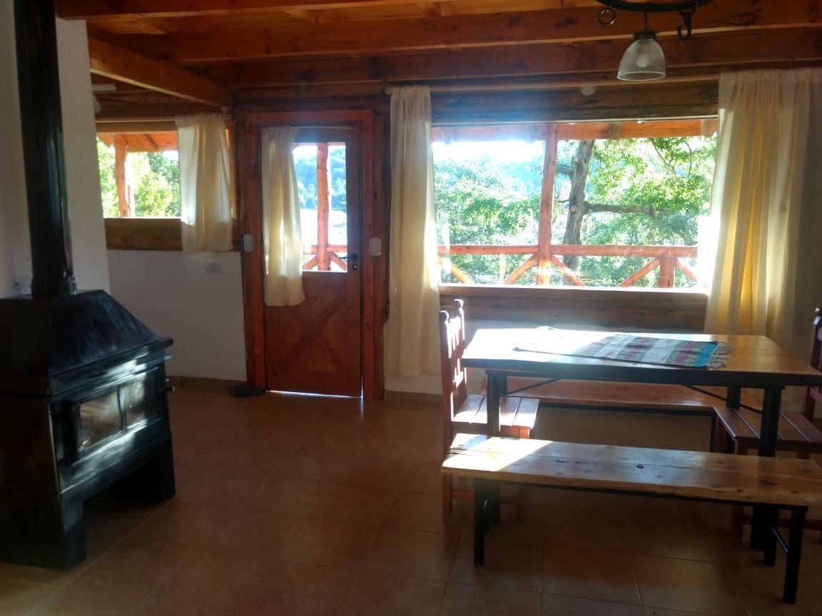 Comedor con bancos de madera y estufa a leña.