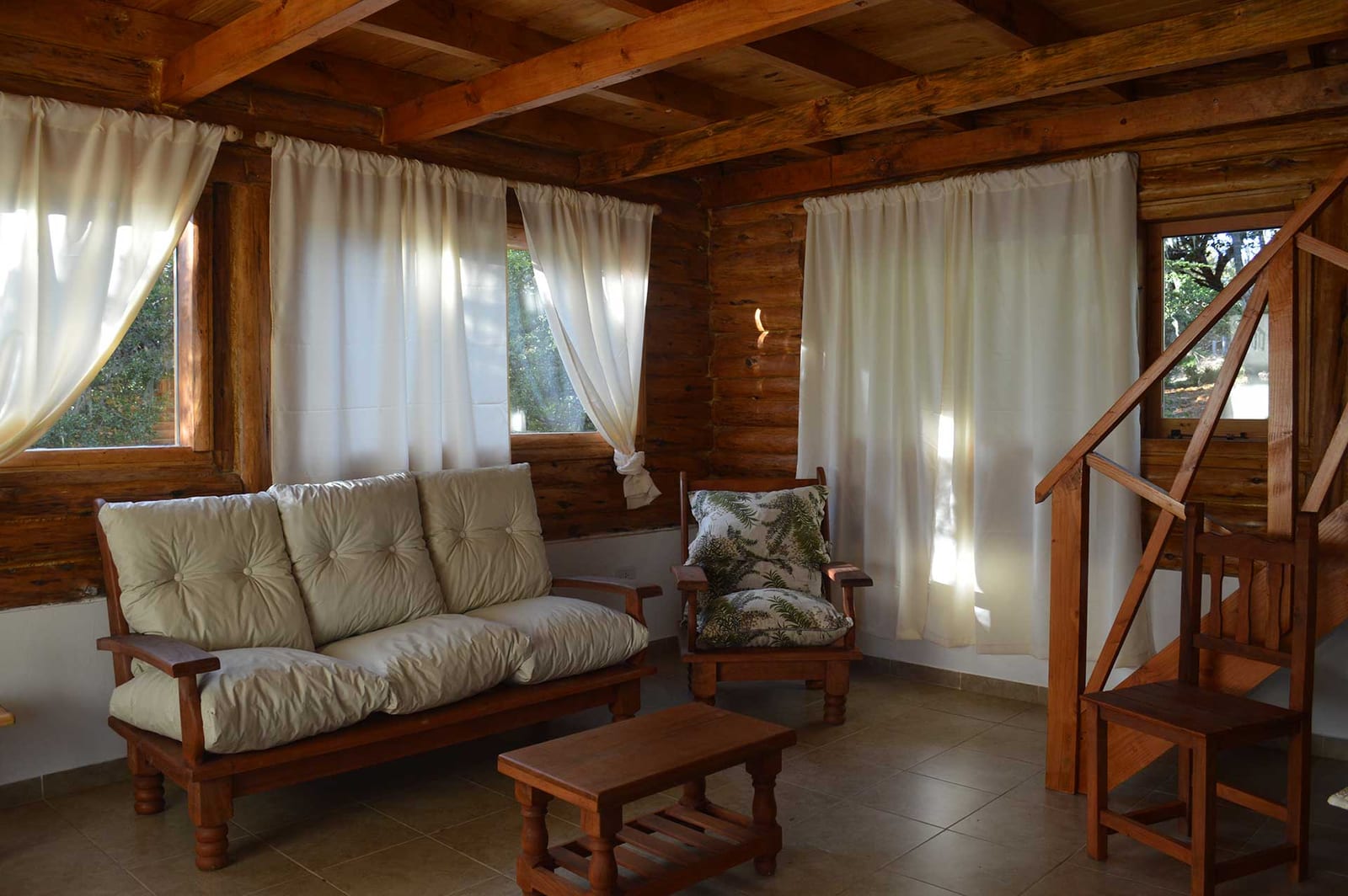 Living con sillón junto a la escalera de madera.