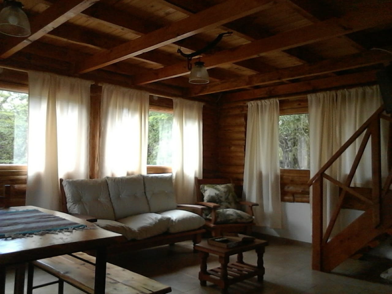 Living con sillón, comedor y escalera al fondo.