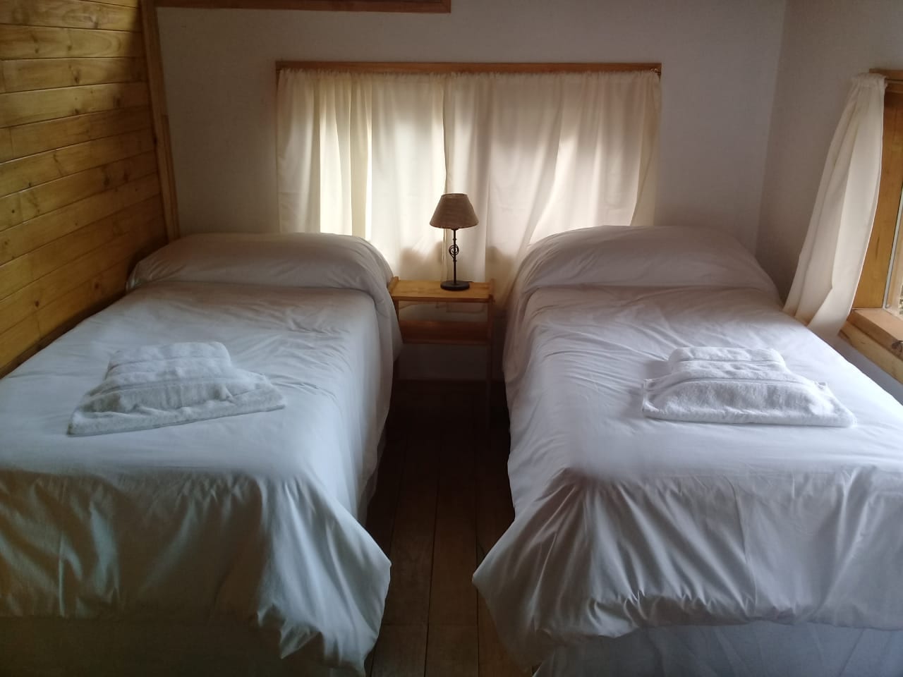 Dormitorio con dos camas individuales y una mesa de luz entre ellas.