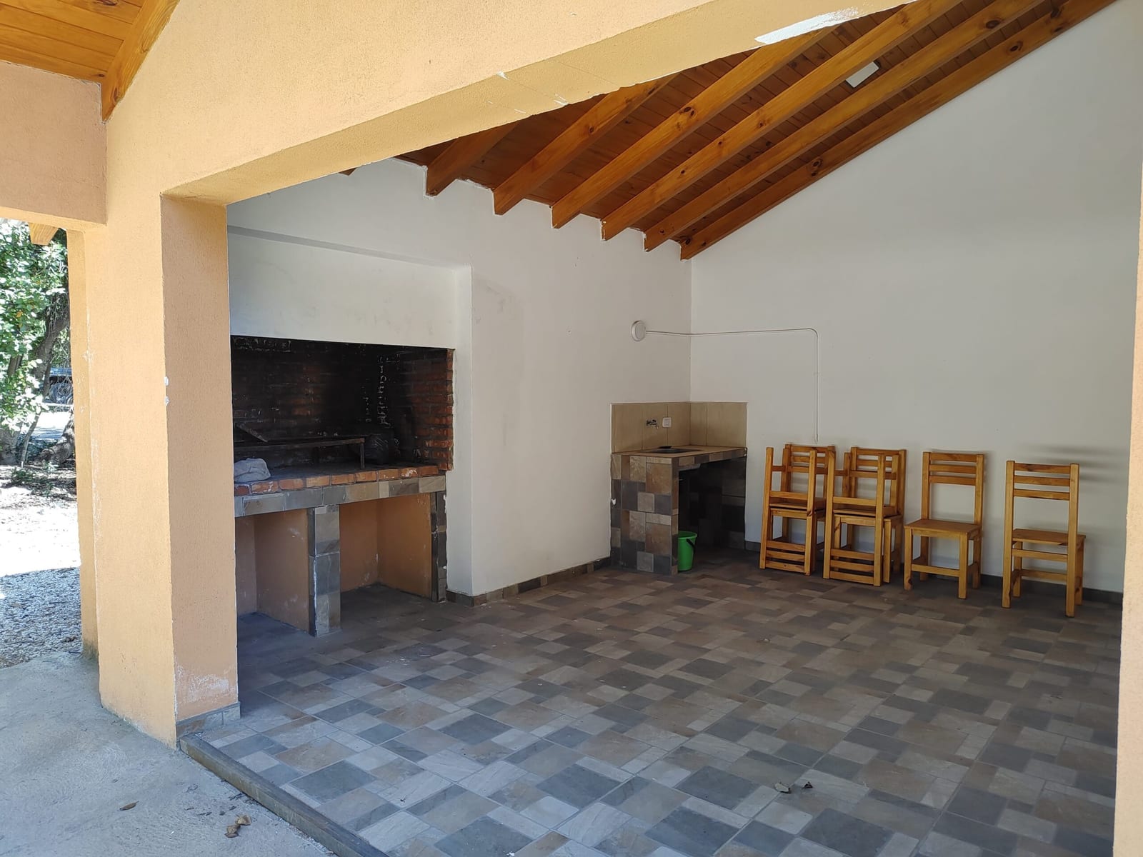 Galería con parrilla y sillas de madera.