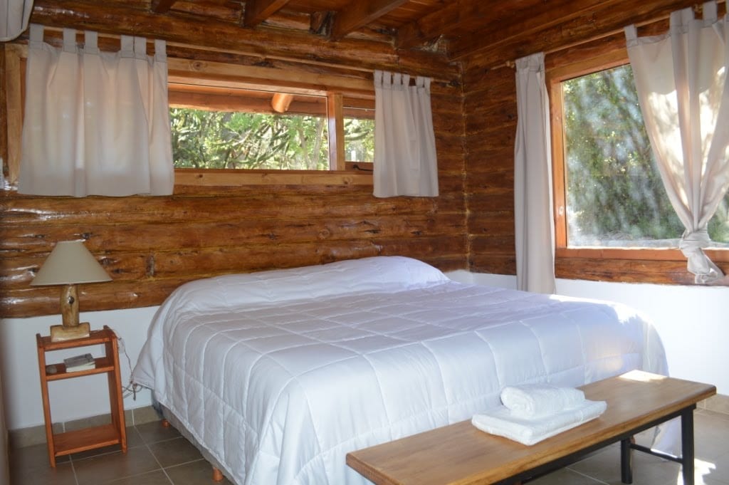 Dormitorio con cama doble y paredes de troncos.