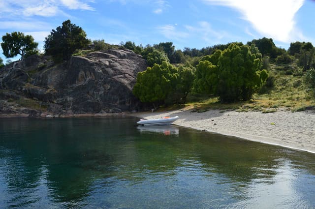 Bote junto a una playa de aguas turquesas y rocas