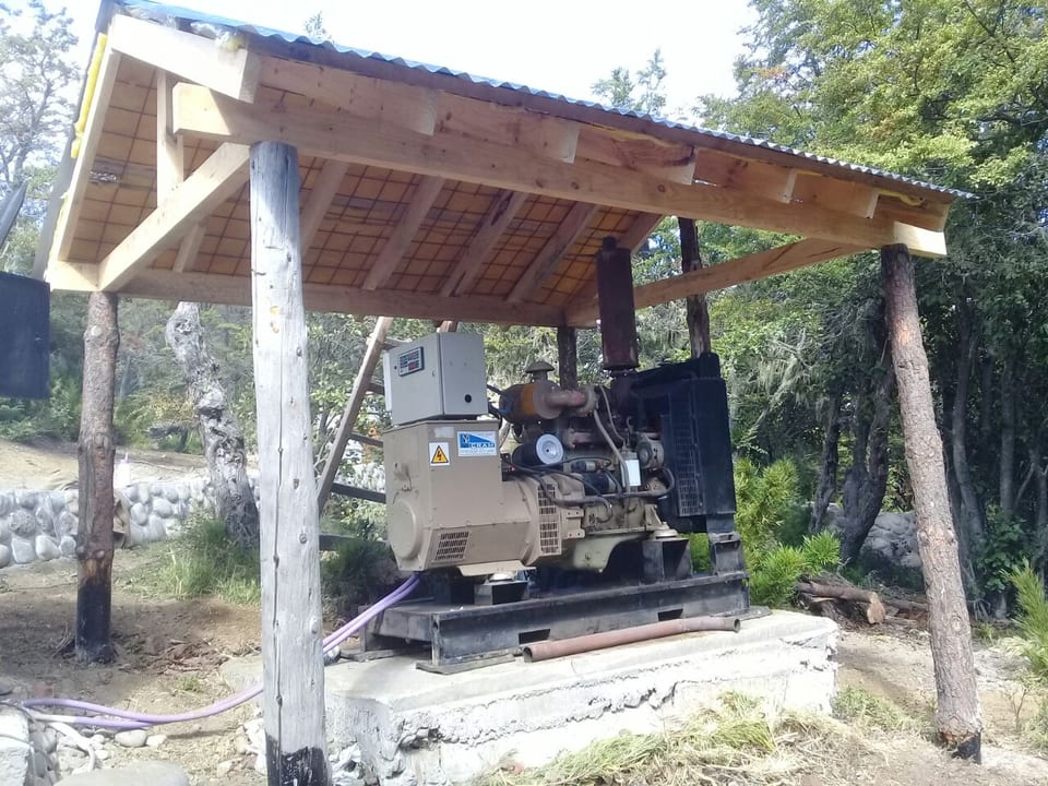 Grupo electrógeno bajo un cobertizo de madera entre árboles